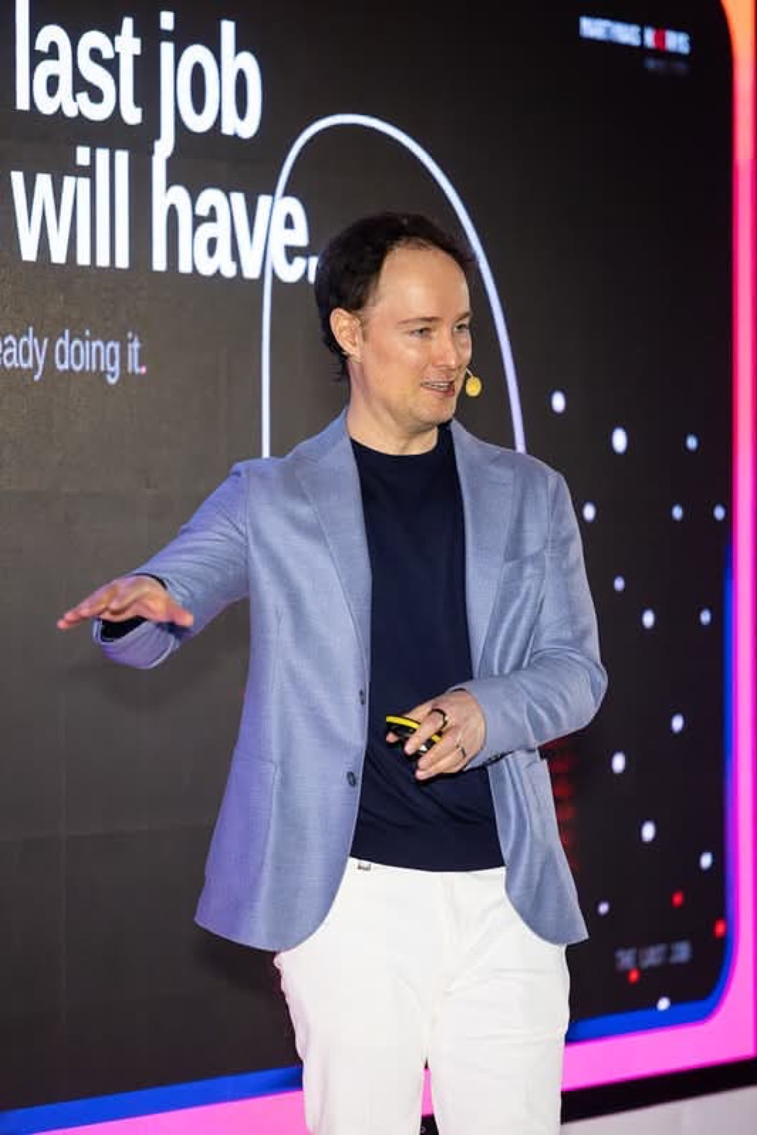 Martynas Kairys on the Vilnius AI Summit stage in a light blazer, gesturing beside the line 'the last job you will have, ready doing it'