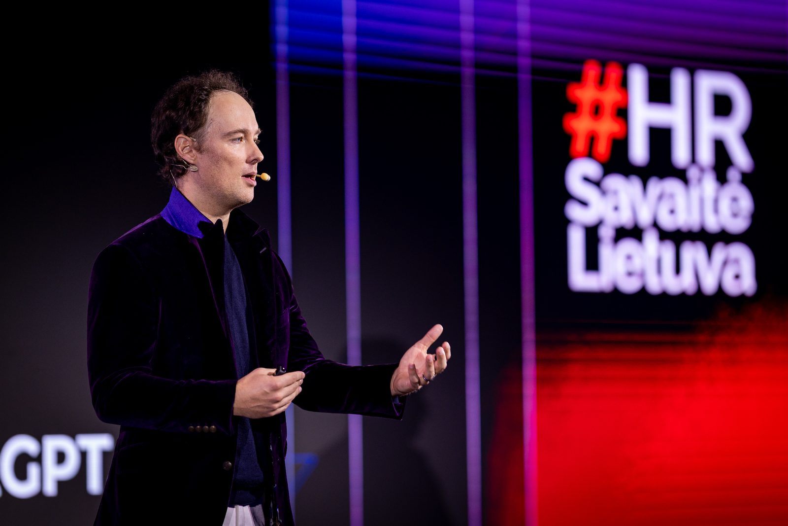 Martynas Kairys speaking on stage at HR Week Lithuania 2026, with the event sign behind him